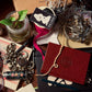 Collection of decorative items including a red notebook, jewelry, and stationery on a wooden surface.