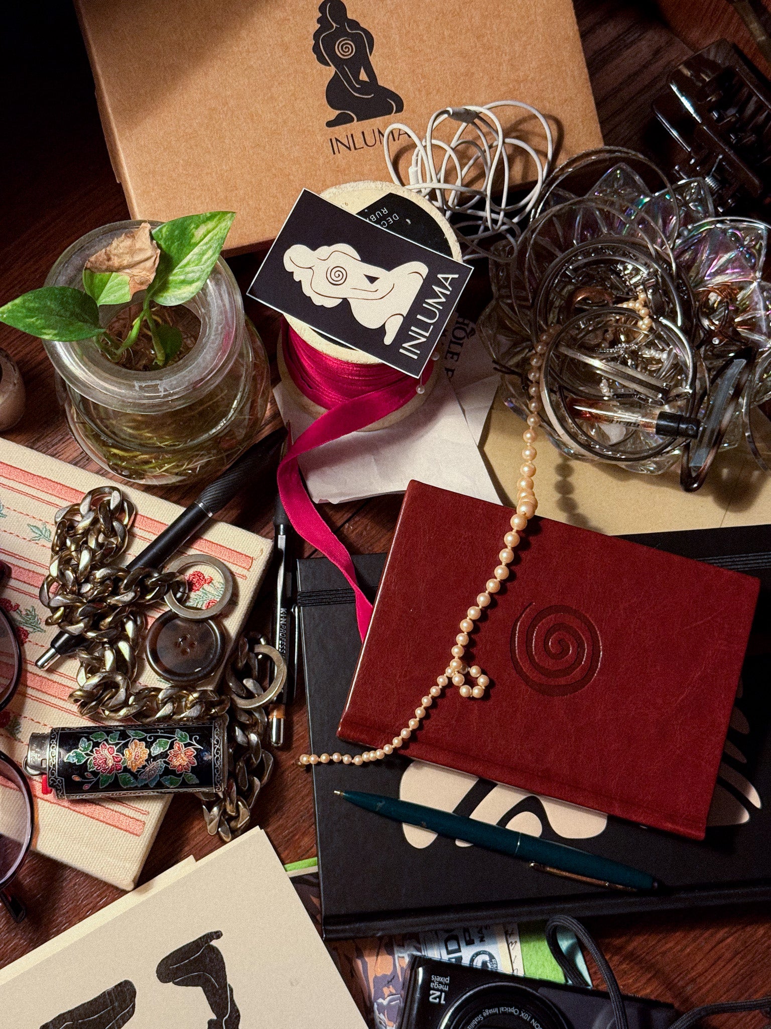 Collection of decorative items including a red notebook, jewelry, and stationery on a wooden surface.